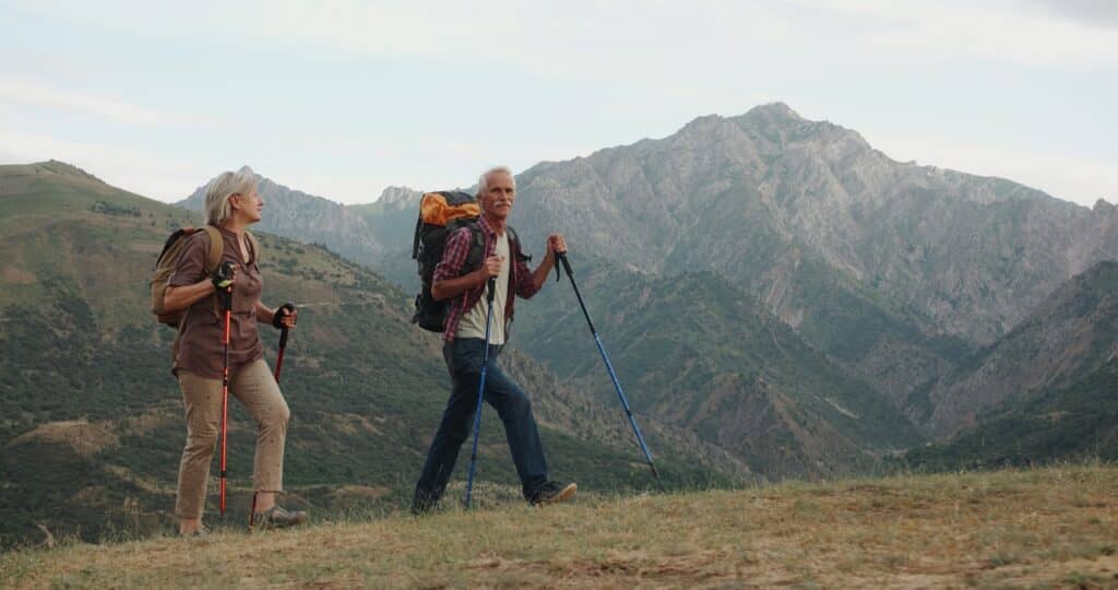 competitive as developer Active senior caucasian couple hiking in mountains with backpacks, enjoying their adventure 4k