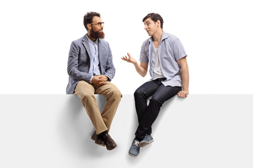 How to mentor a junior developer Full length shot of men sitting on a banner and talking isolated on white background