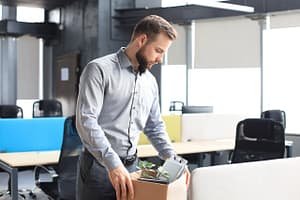 Sad dismissed worker taking his office supplies with him from office